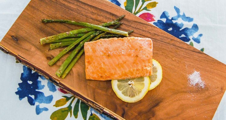 fish on a cutting board with asparagus, lemon, and salt