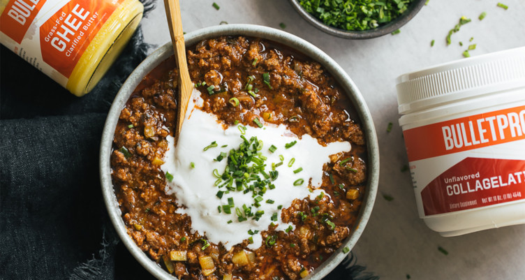 bowl of chili topped with sour cream and herbs