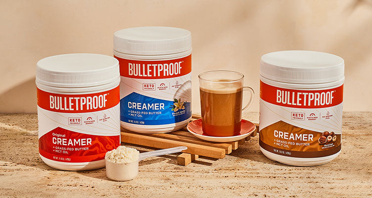 Canisters of Bulletproof coffee creamer next to a cup of coffee