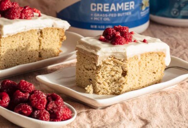 Slice of Keto Tres Leches cake sitting next to bowl of raspberries