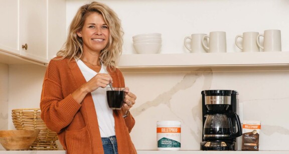 Blonde woman leaning on kitchen counter drinking Bulletproof Innerfuel Prebiotic Coffee