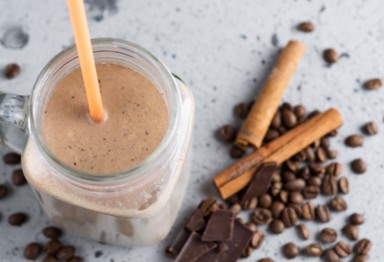 A mason jar of a coffee smoothie with cinnamon sticks