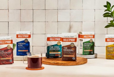 Bulletproof Ground Coffee product line on counter with cup of hot coffee