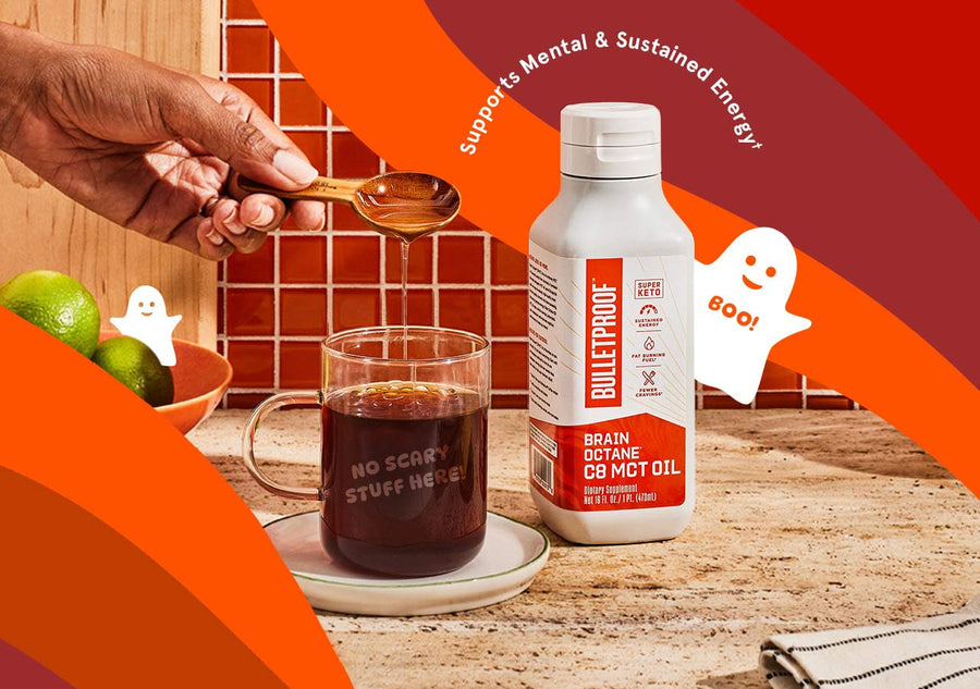 Bulletproof C8 MCT Oil on a counter with a mug of coffee and a hand pouring oil into it. Supports mental and sustained energy. Boo! No scary stuff here! 