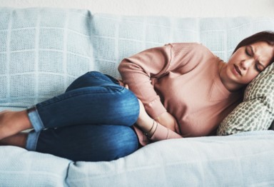 Woman on couch with stomach ache.